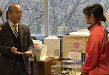 星野さんが獲得した銅メダルを学長に渡して見せている様子