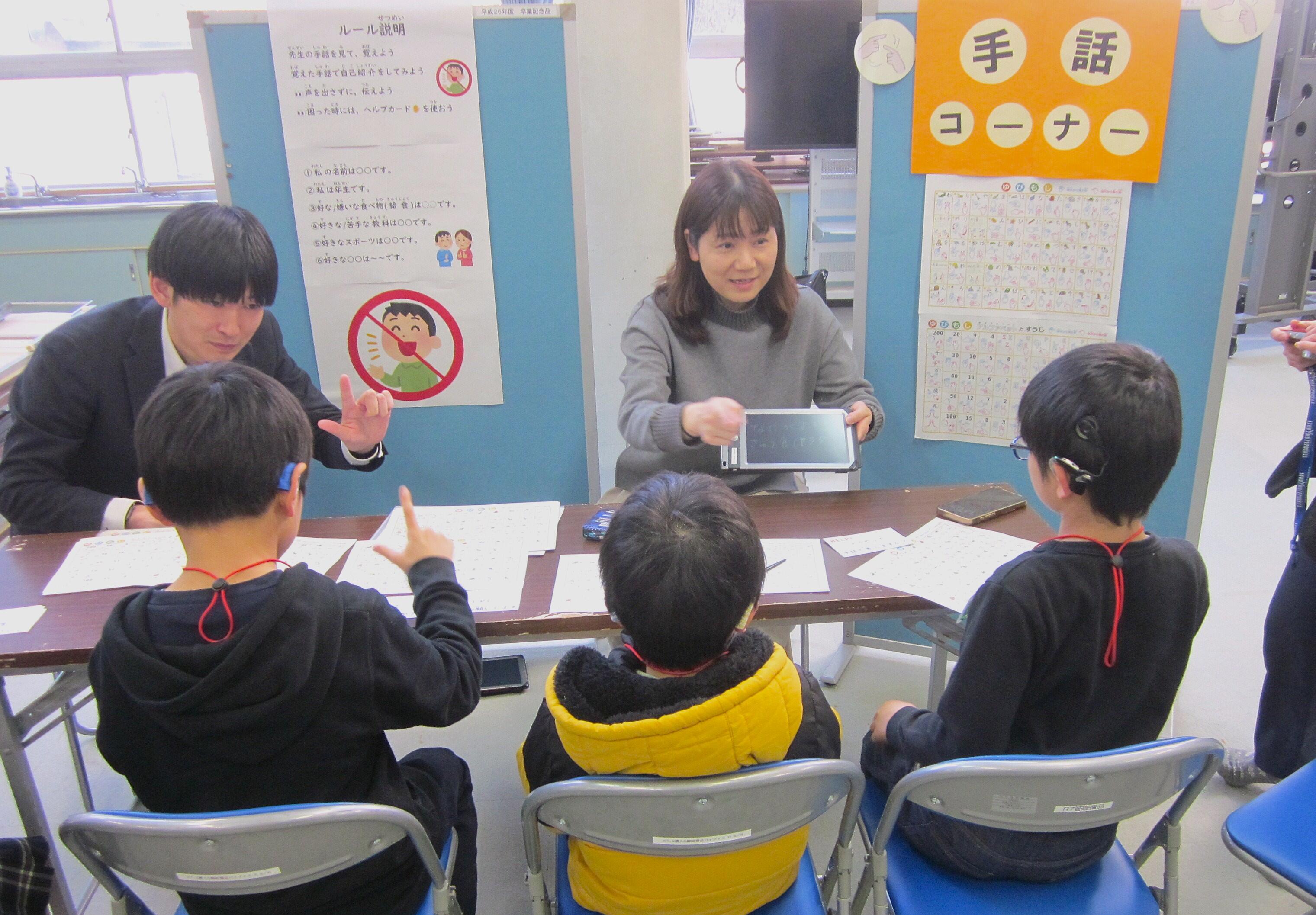 手話体験コーナーで本学教員が児童に手話を教えている様子
